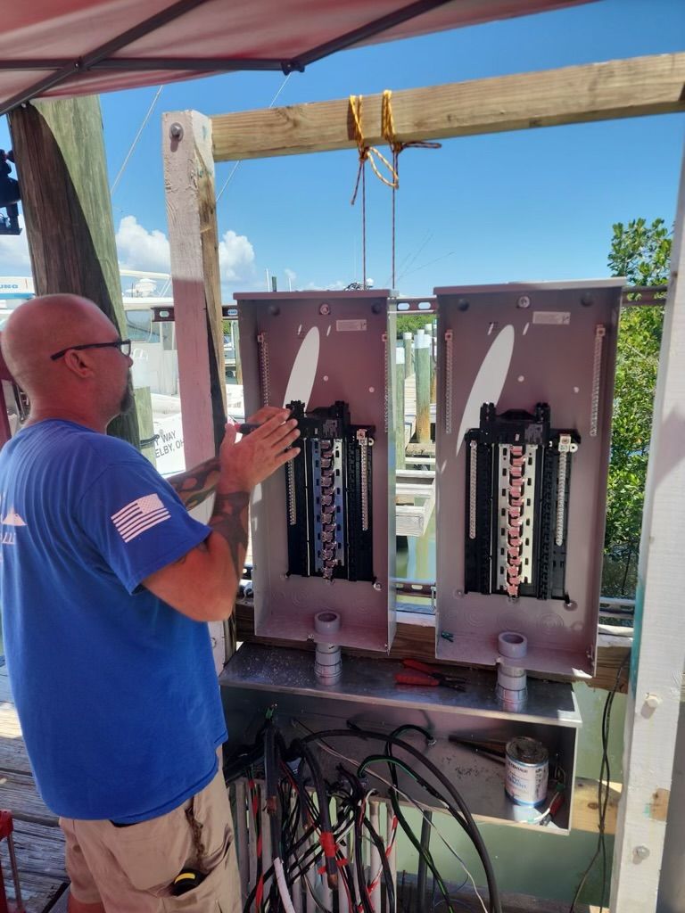 A man in a blue shirt is working on a electrical box.