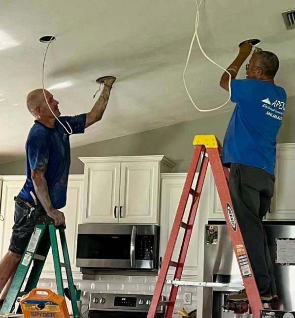 Two men are working on a ceiling in a kitchen