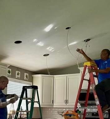 Two men are working on a ceiling in a kitchen.