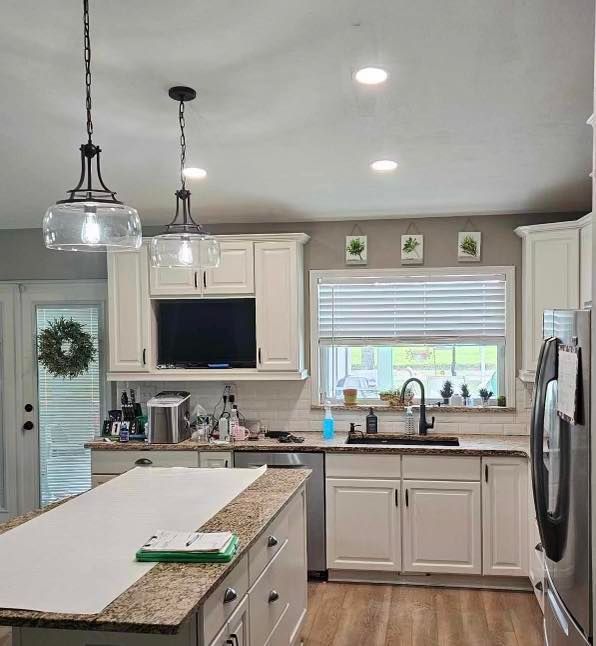 A kitchen with white cabinets , granite counter tops , stainless steel appliances and a large island.