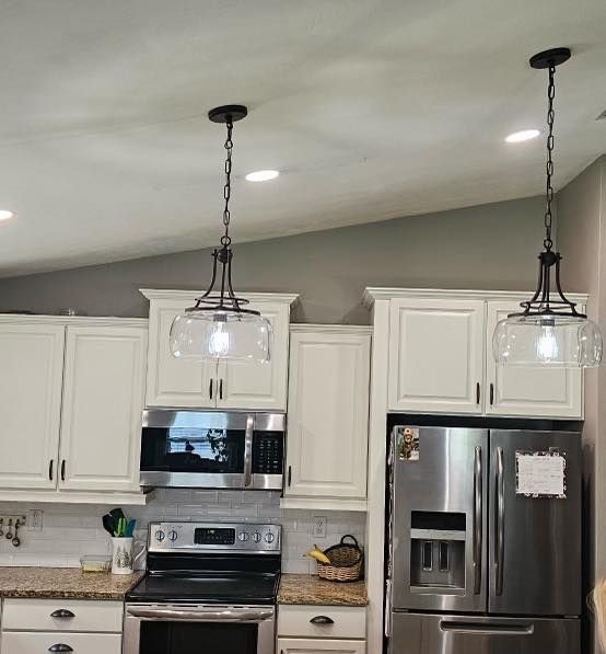 A kitchen with white cabinets , stainless steel appliances , a refrigerator and a microwave.