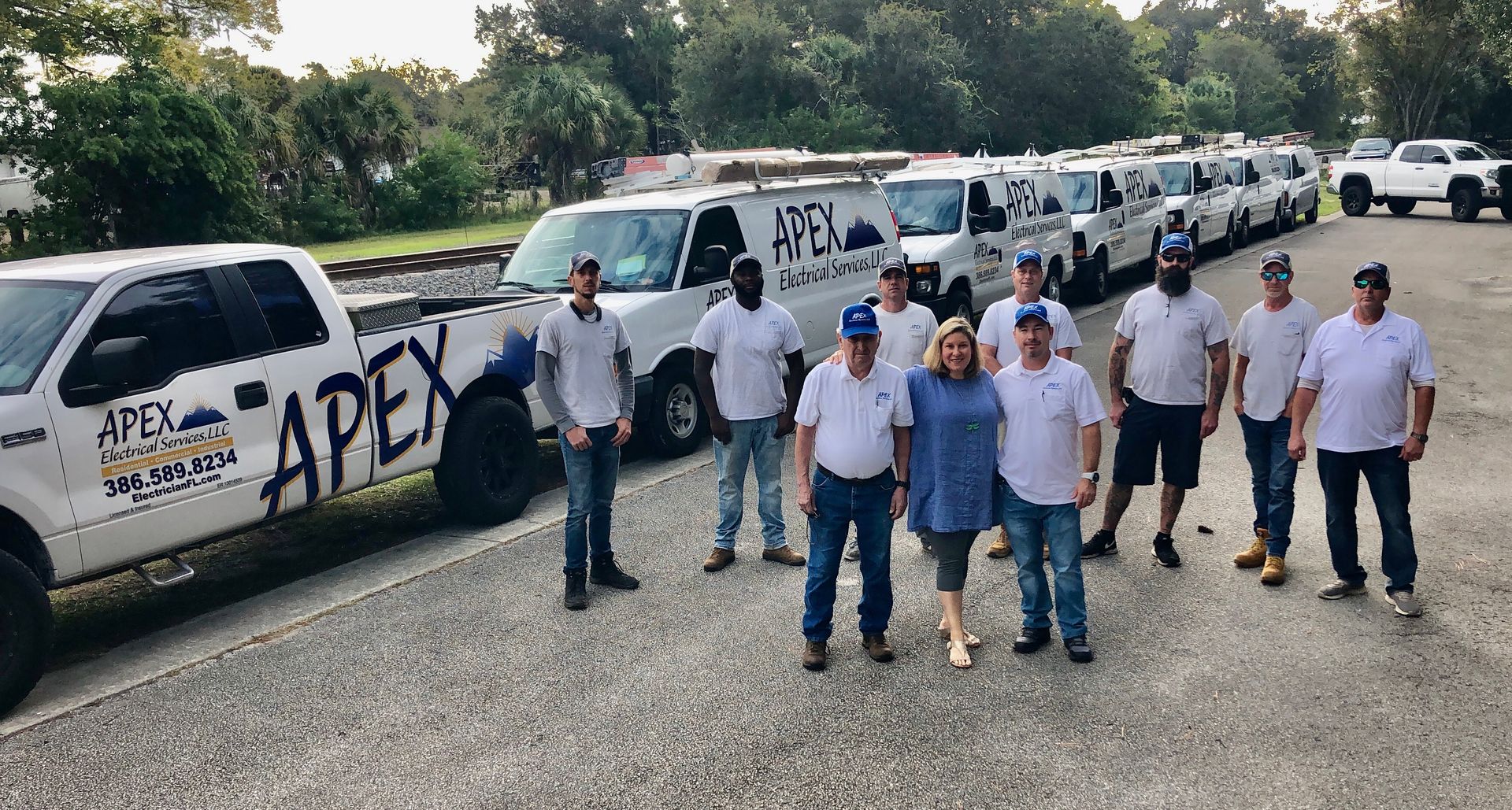 Team of HVAC workers posing with their company vans and truck.
