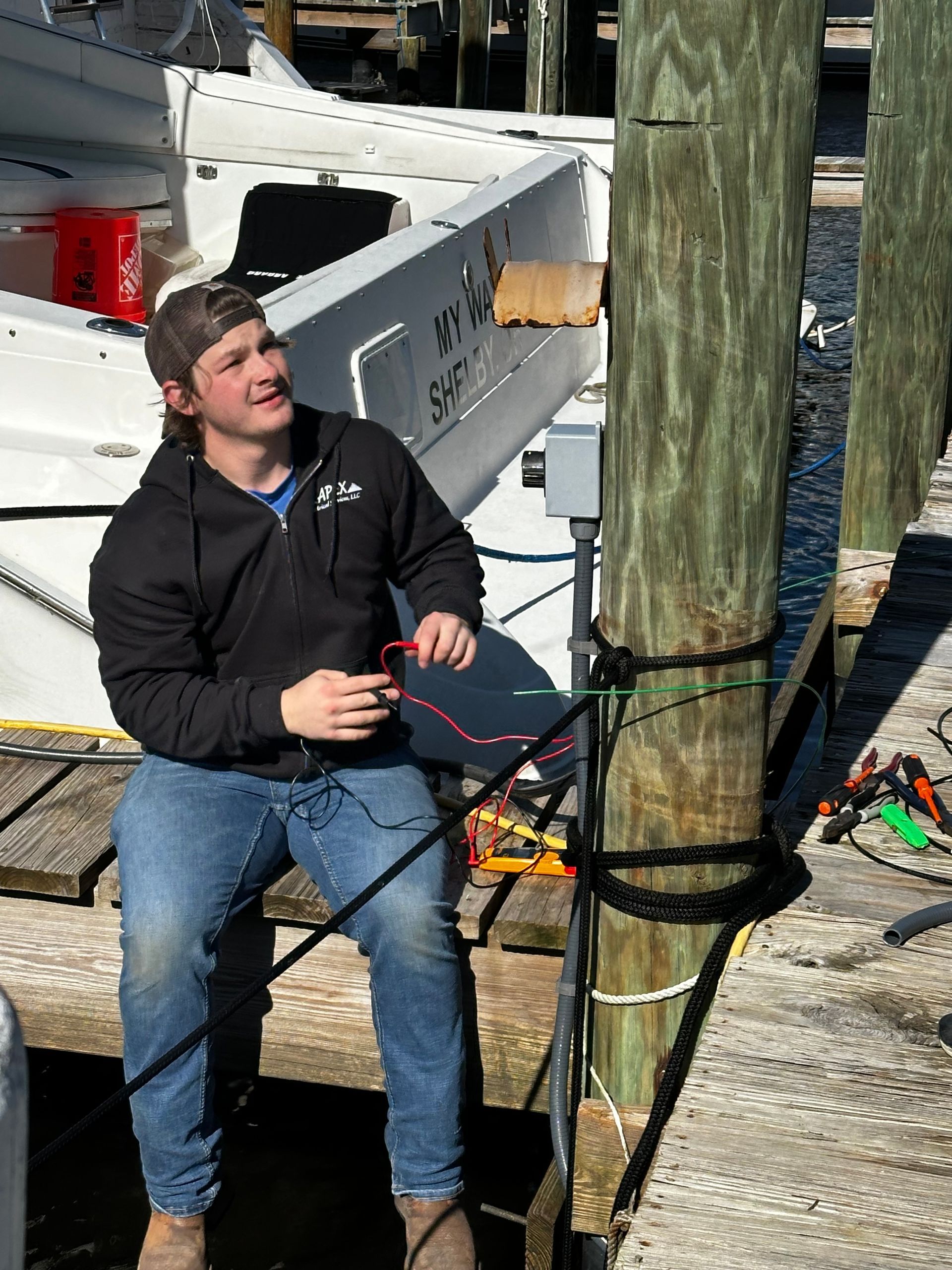 a man is sitting on a dock next to a boat that says sya