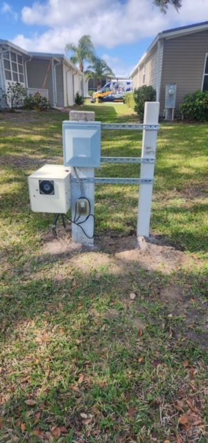 A blue mailbox is sitting in the grass in front of a house.