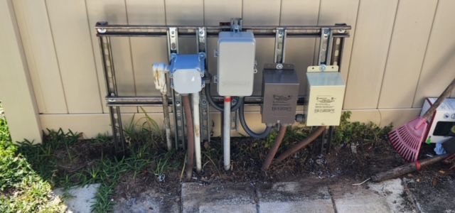 A bunch of electrical boxes are sitting on the side of a building.
