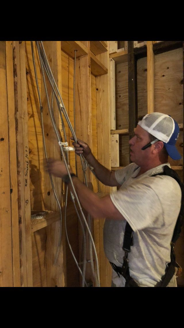 a man in a white shirt and blue hat is working on electrical wires