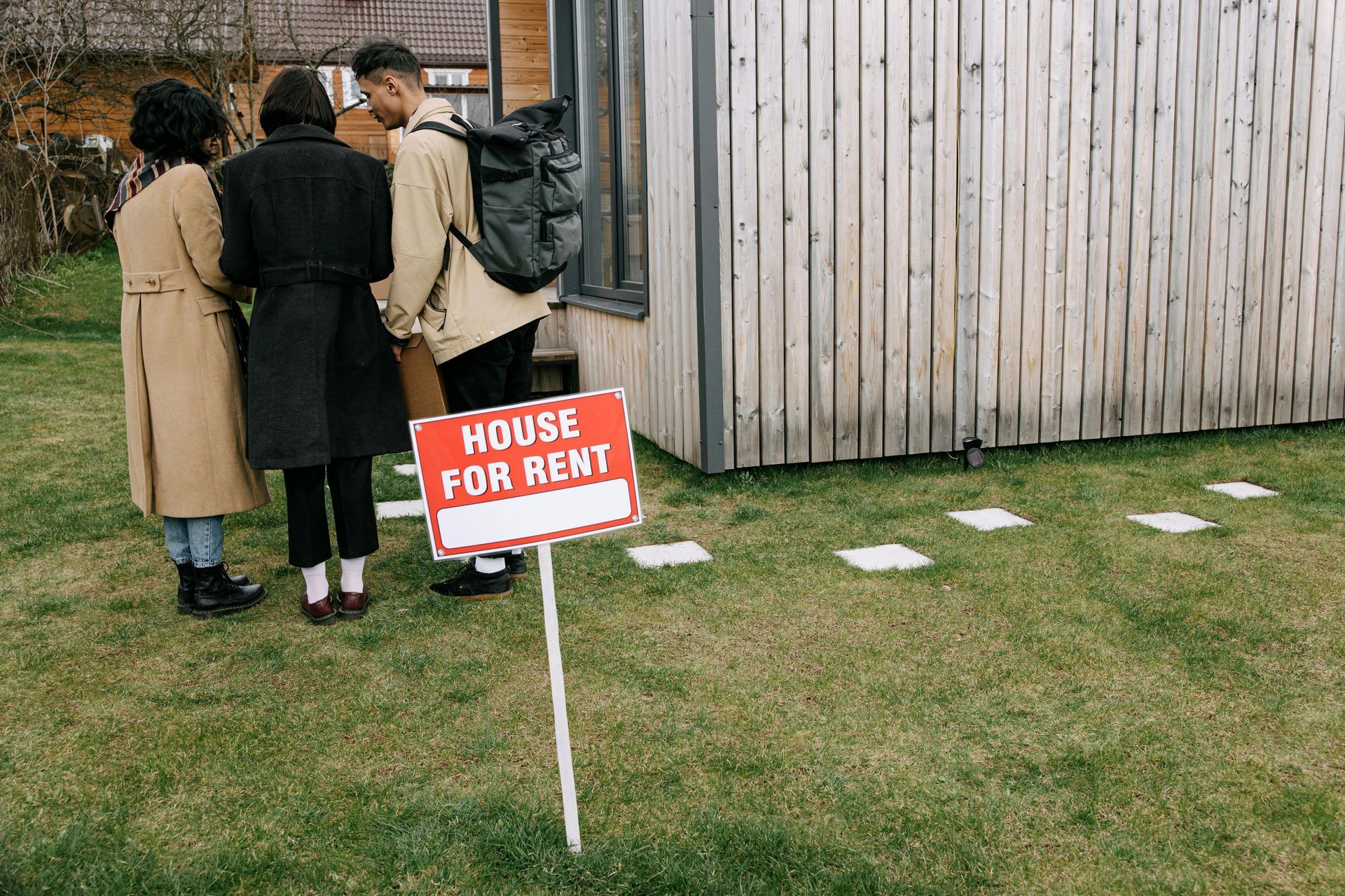 Three people viewing a house for rent; a red