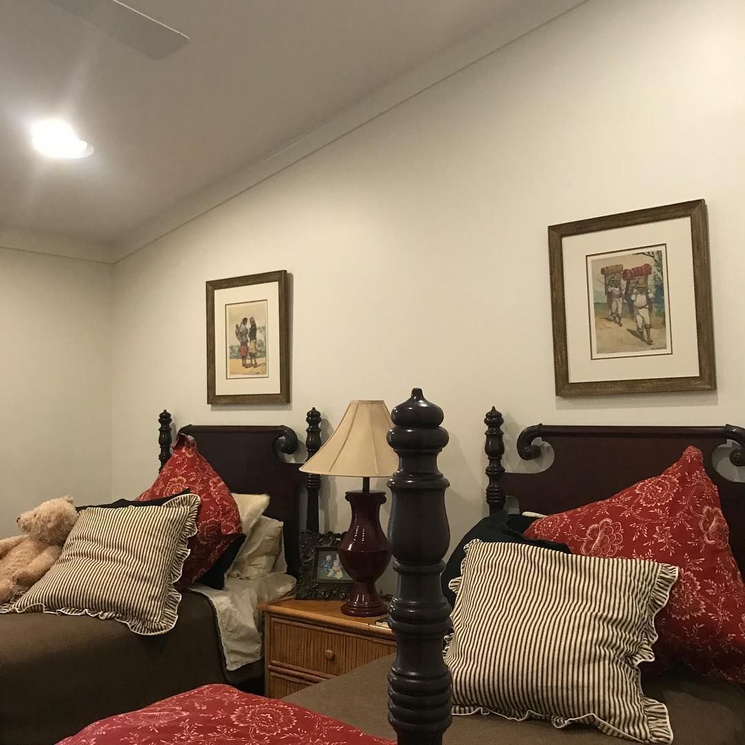 A bedroom with two beds , two lamps , and two pictures on the wall.