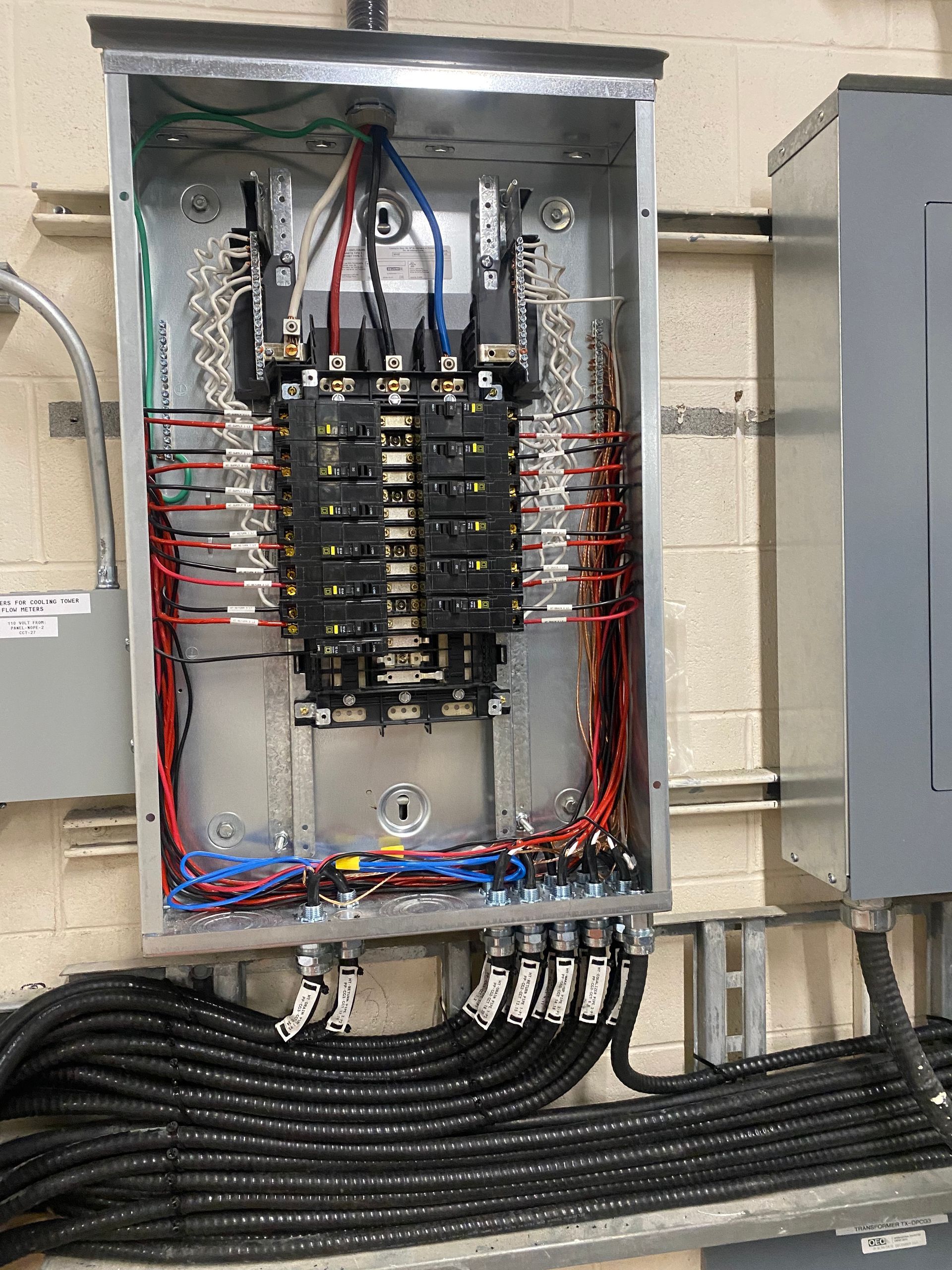 Open electrical panel with wires and circuit breakers.