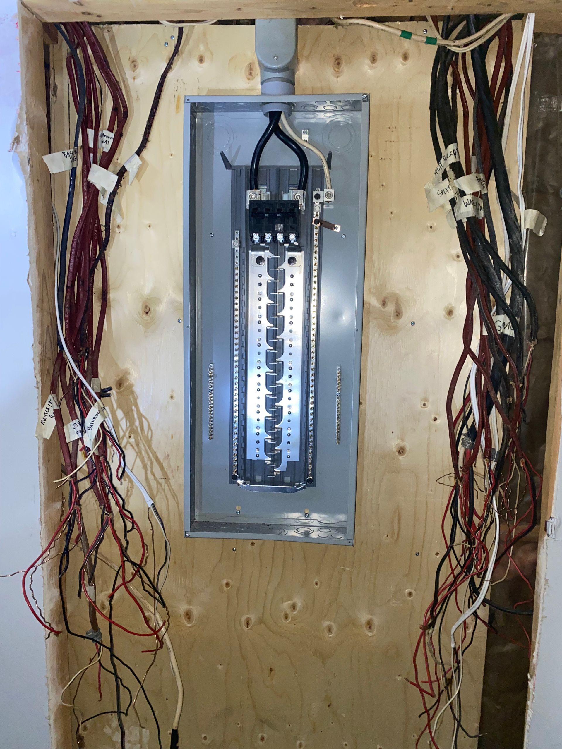 Electrical panel installed on a wooden wall, with numerous wires extending to the left and right.