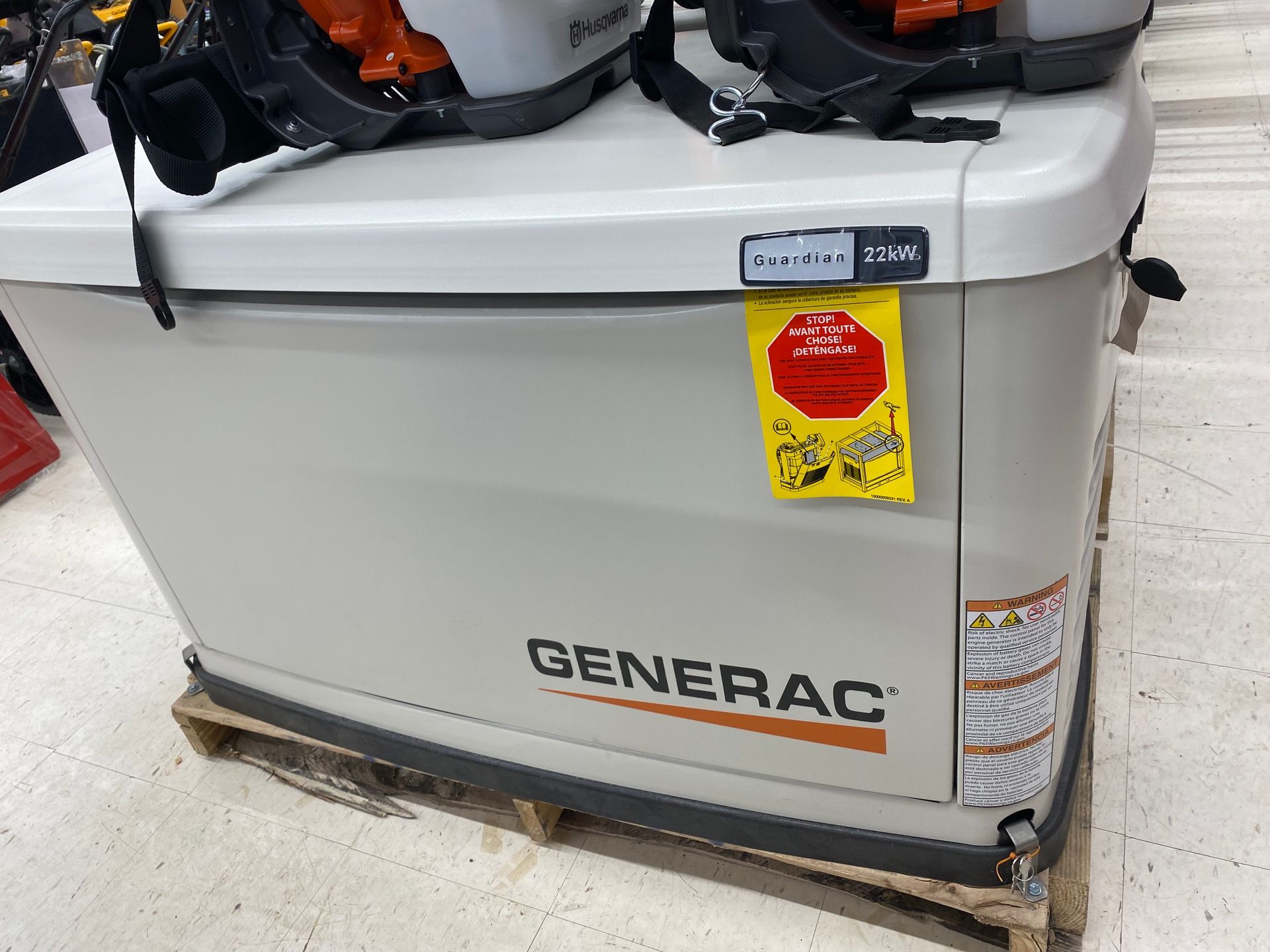 Generac generator on a pallet with warning tag and leaf blower on top.