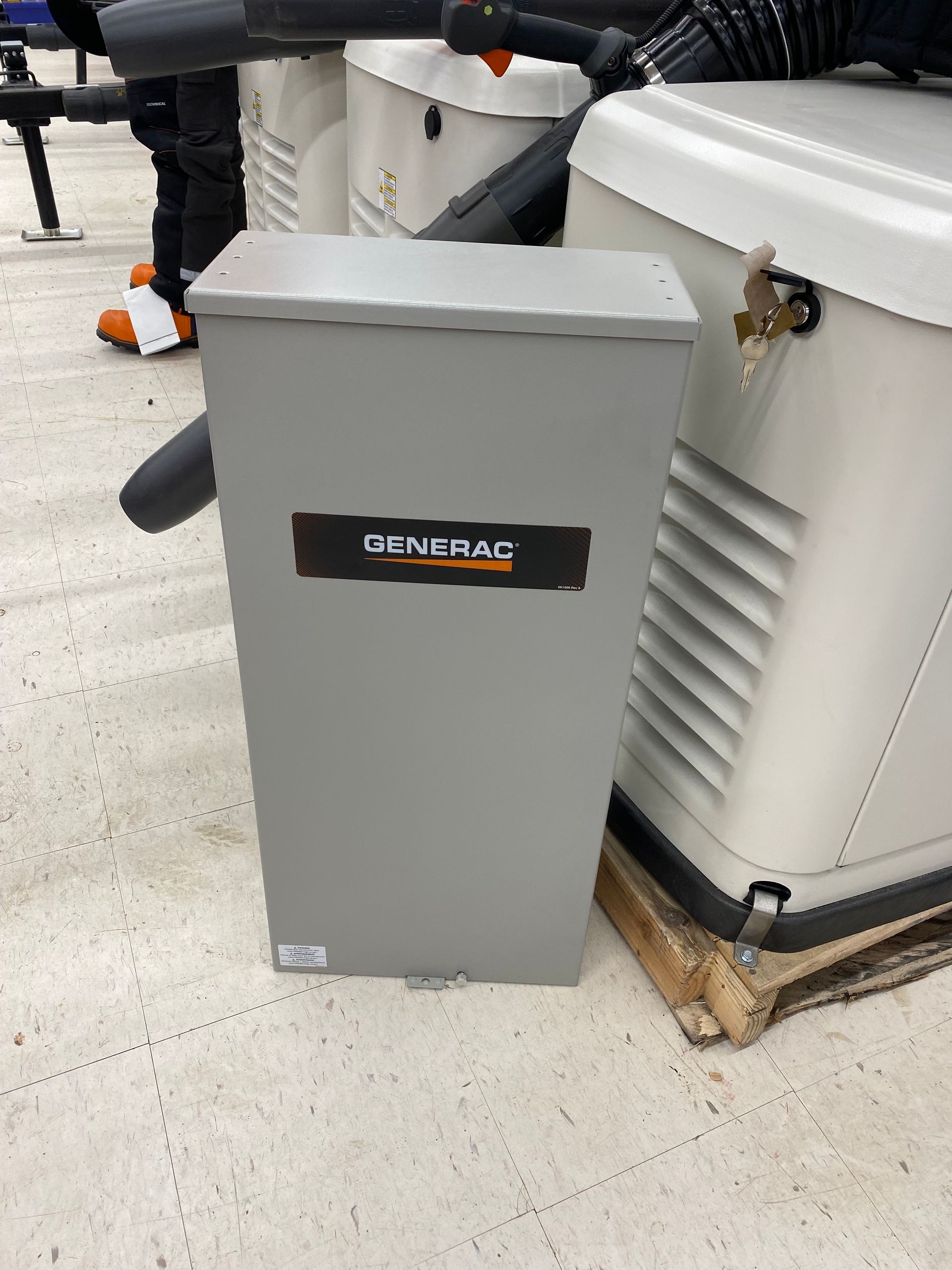 Gray Generac transfer switch box next to a white generator.