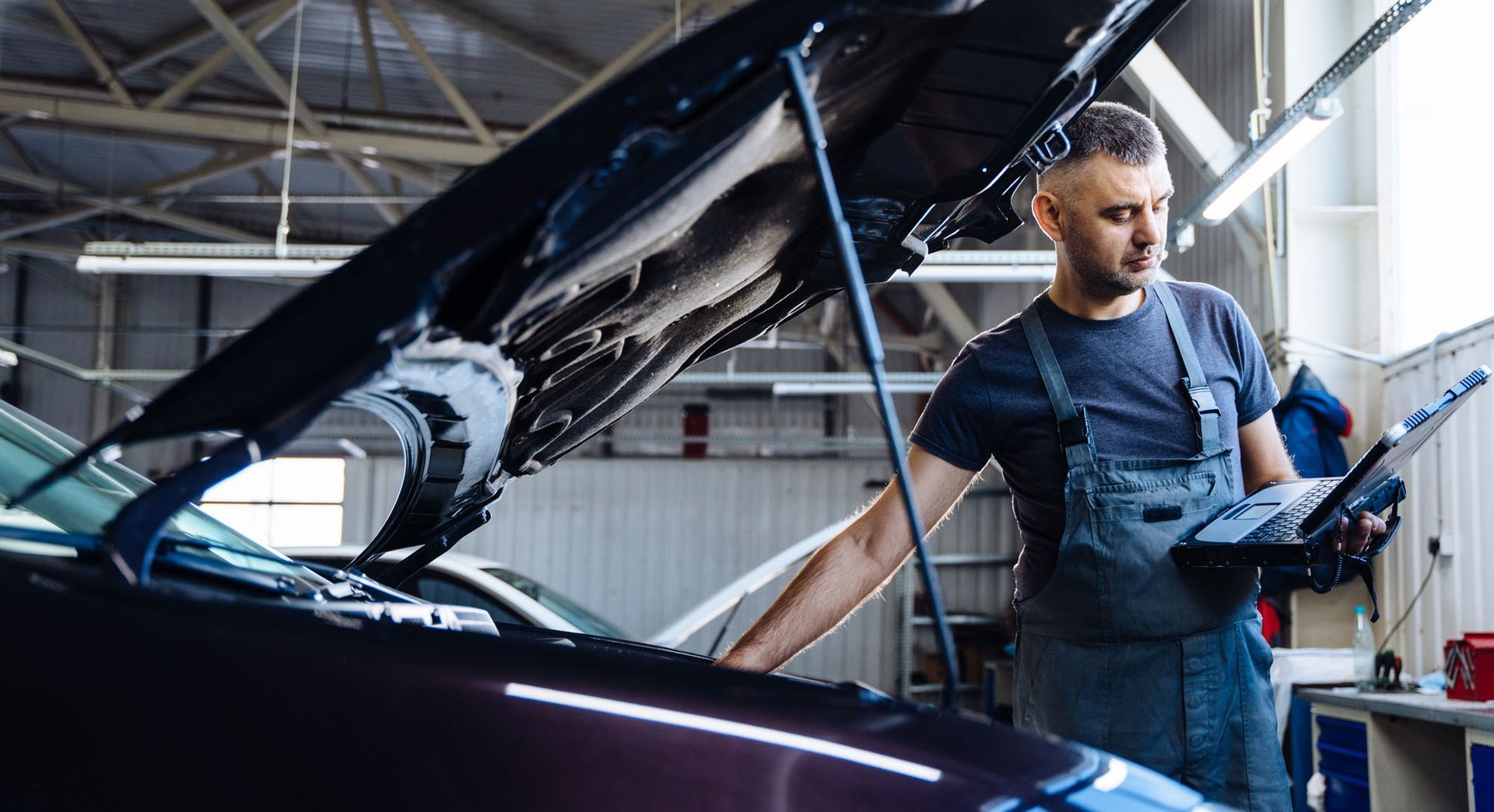 A person in gloves sands a car bumper in a workshop.