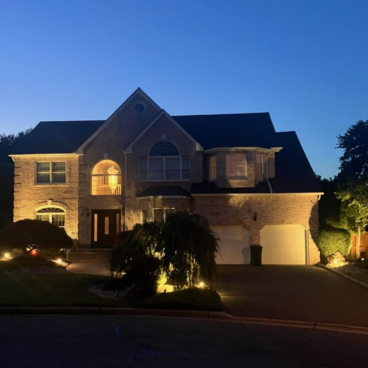 Two-story brick home in Edison, NJ illuminated with professional low-voltage landscape lighting installed by JDP Electric