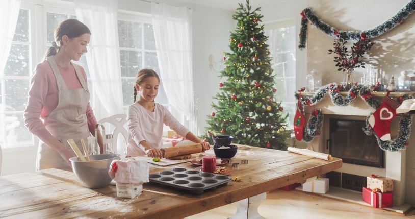 a woman and child are preparing christmas cookies in front of a christmas tree