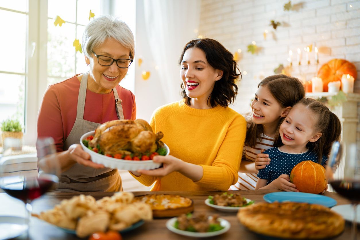 Family preparing a Thanksgiving meal in a cozy kitchen holding a turkey with pie on the counter