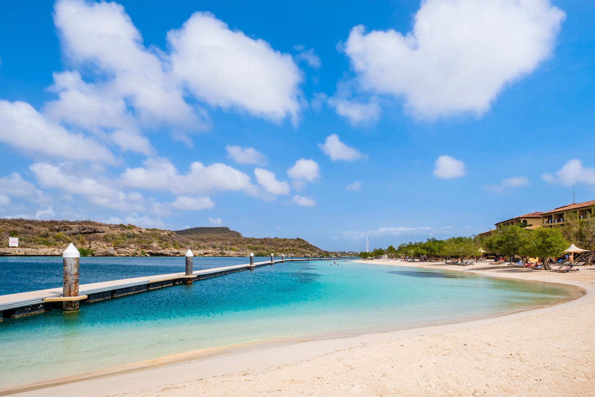 A woman in a life jacket is pointing at something while sitting on a boat.