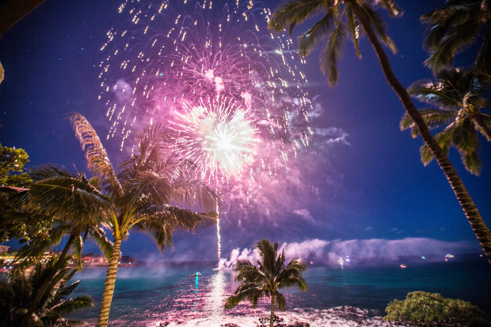 A woman in a life jacket is pointing at something while sitting on a boat.