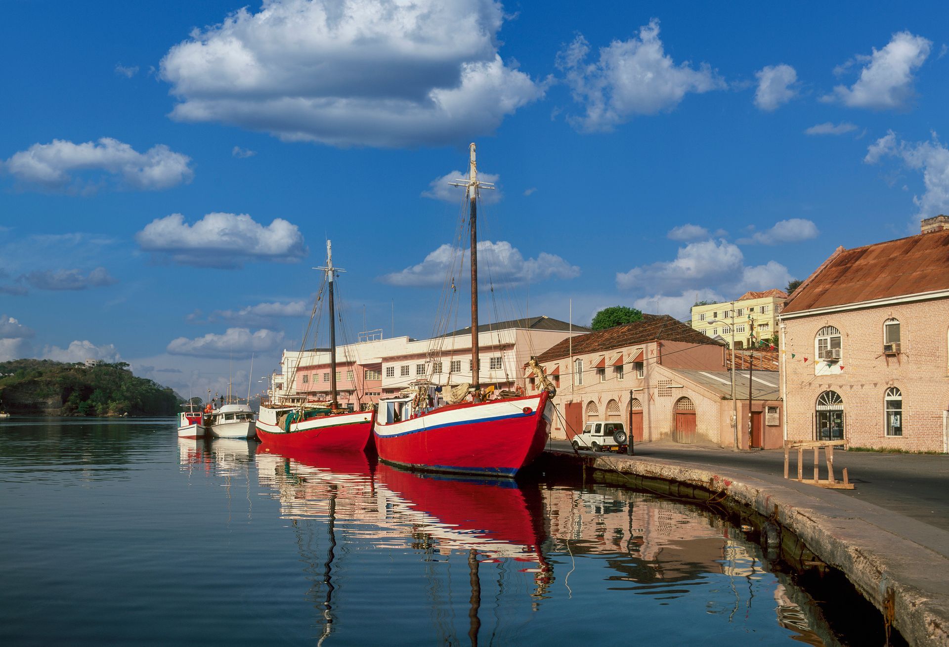 A woman in a life jacket is pointing at something while sitting on a boat.