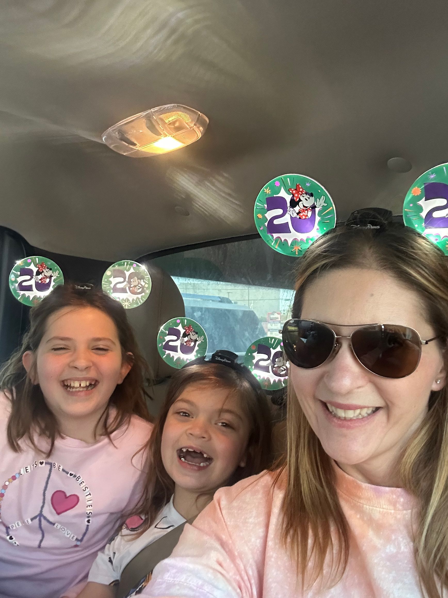 Woman and two smiling children in a car. Balloons with 