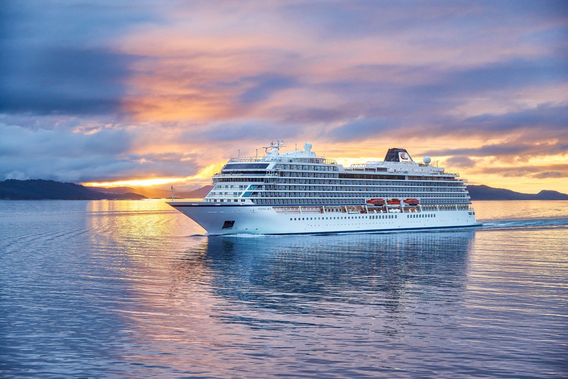 A cruise ship is floating on top of a body of water at sunset.