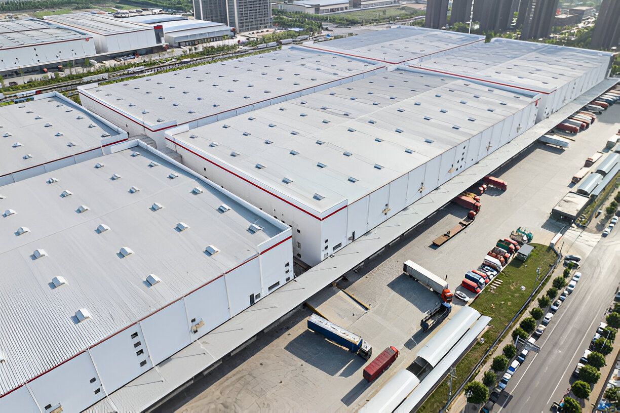 Aerial view of a large warehouse complex with trucks parked at loading docks, in a city setting.