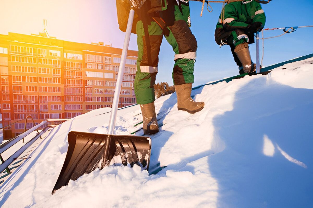 Workers shoveling snow from a rooftop.