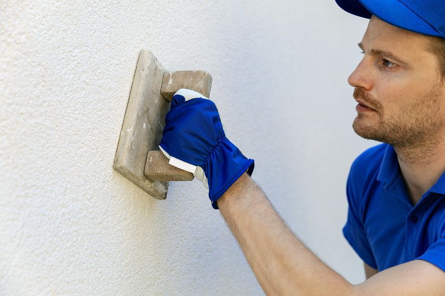 A man is using a trowel to plaster a wall.