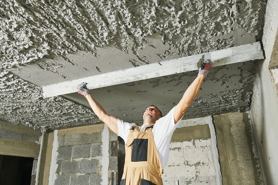 A man is plastering a ceiling with a trowel.