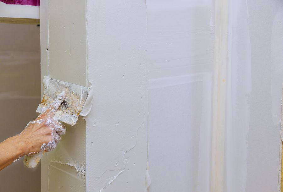 A person is plastering a wall with a spatula.