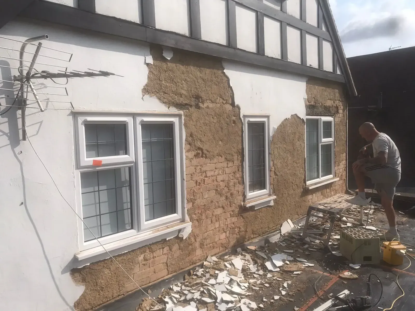 Rear elevation with failed render removed back to brick during preparation for a two-coat OCR render system.