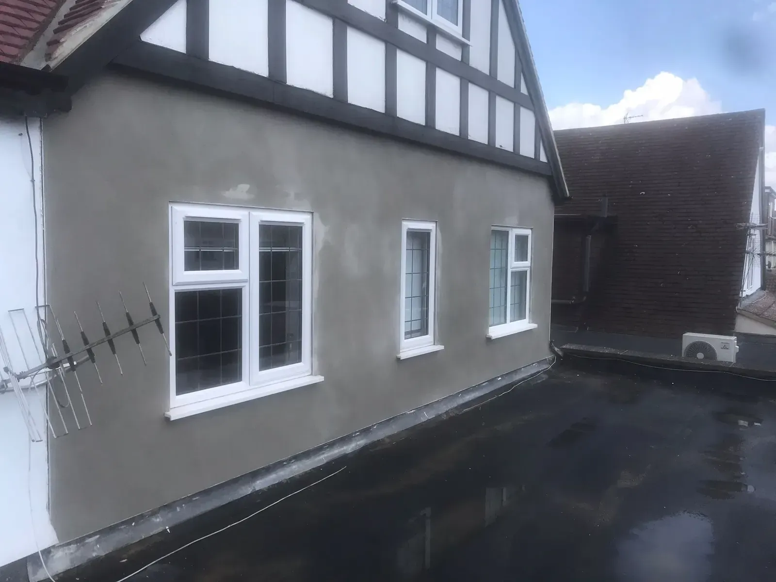 Freshly applied cementitious OCR render coat on the repaired wall, creating a smooth, paint-ready finish.