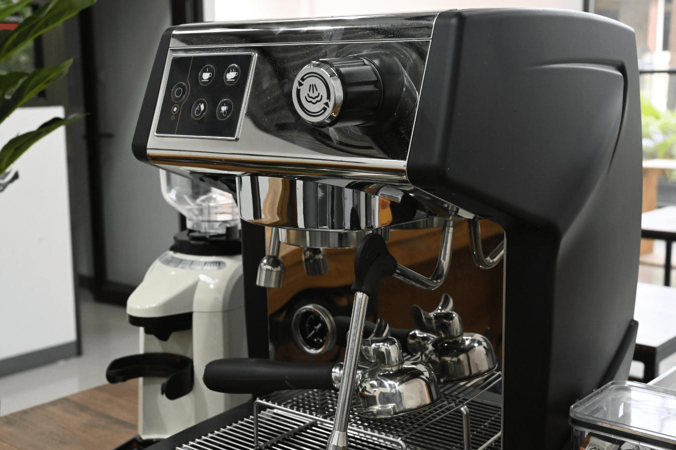 A coffee machine is sitting on a counter next to a grinder.