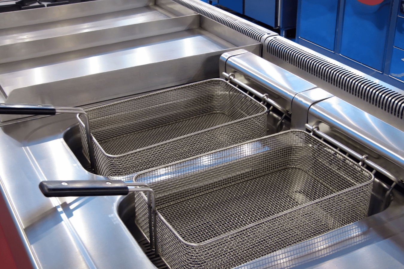 Two frying baskets are sitting on top of a stainless steel counter.
