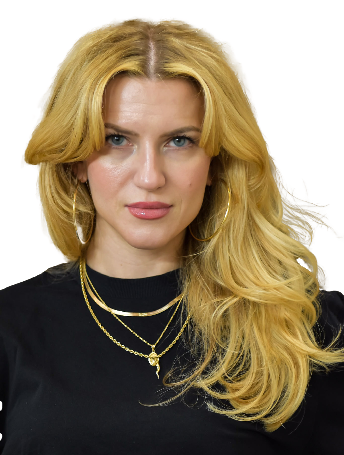 Blonde woman in black top with tattoos; looks at the camera.
