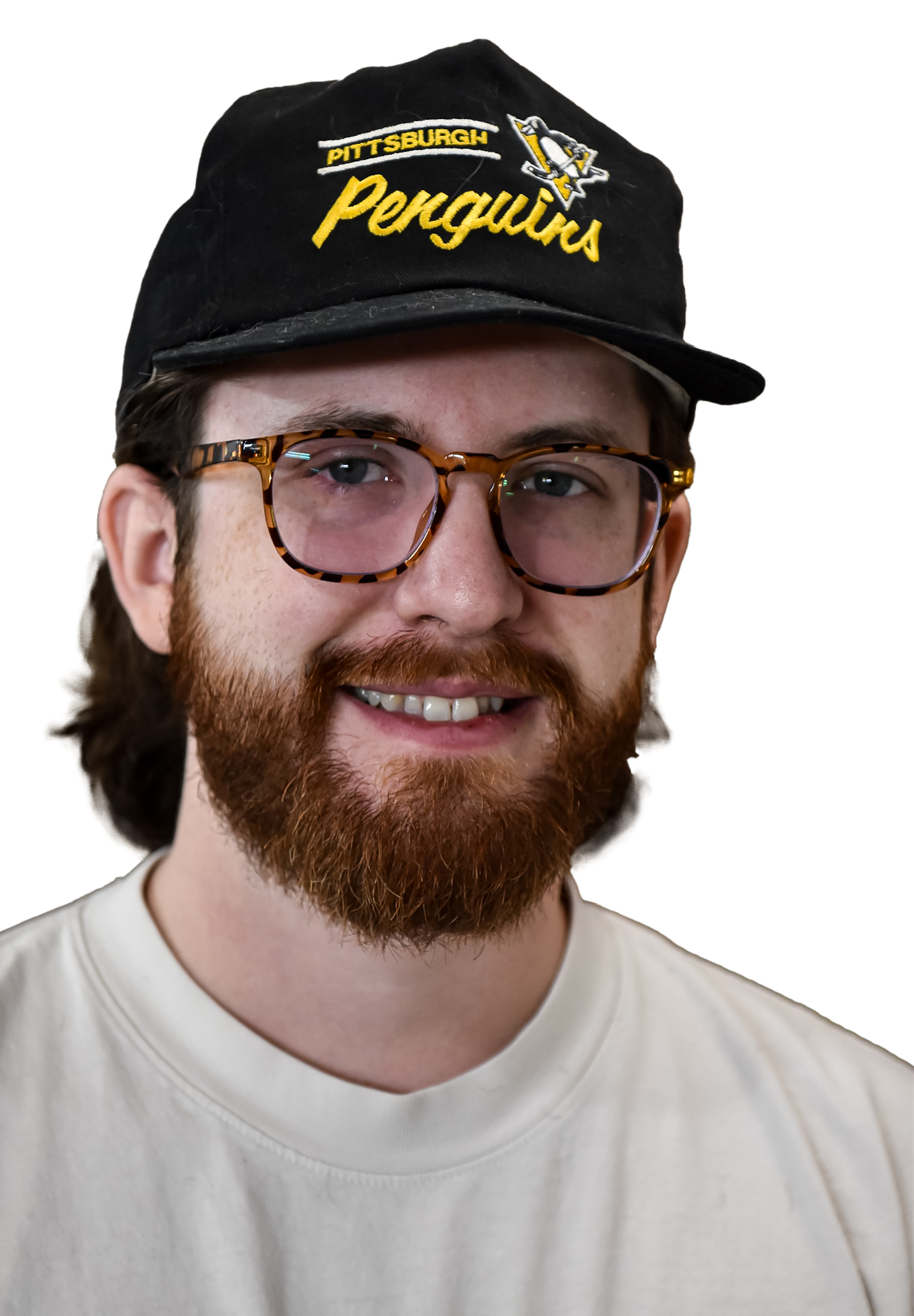 Man with glasses and beard wearing a cap. Black t-shirt with graphic.