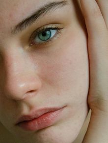 Close-up of a fair-skinned person with blue-green eyes gazing softly. Light blush on the cheeks.