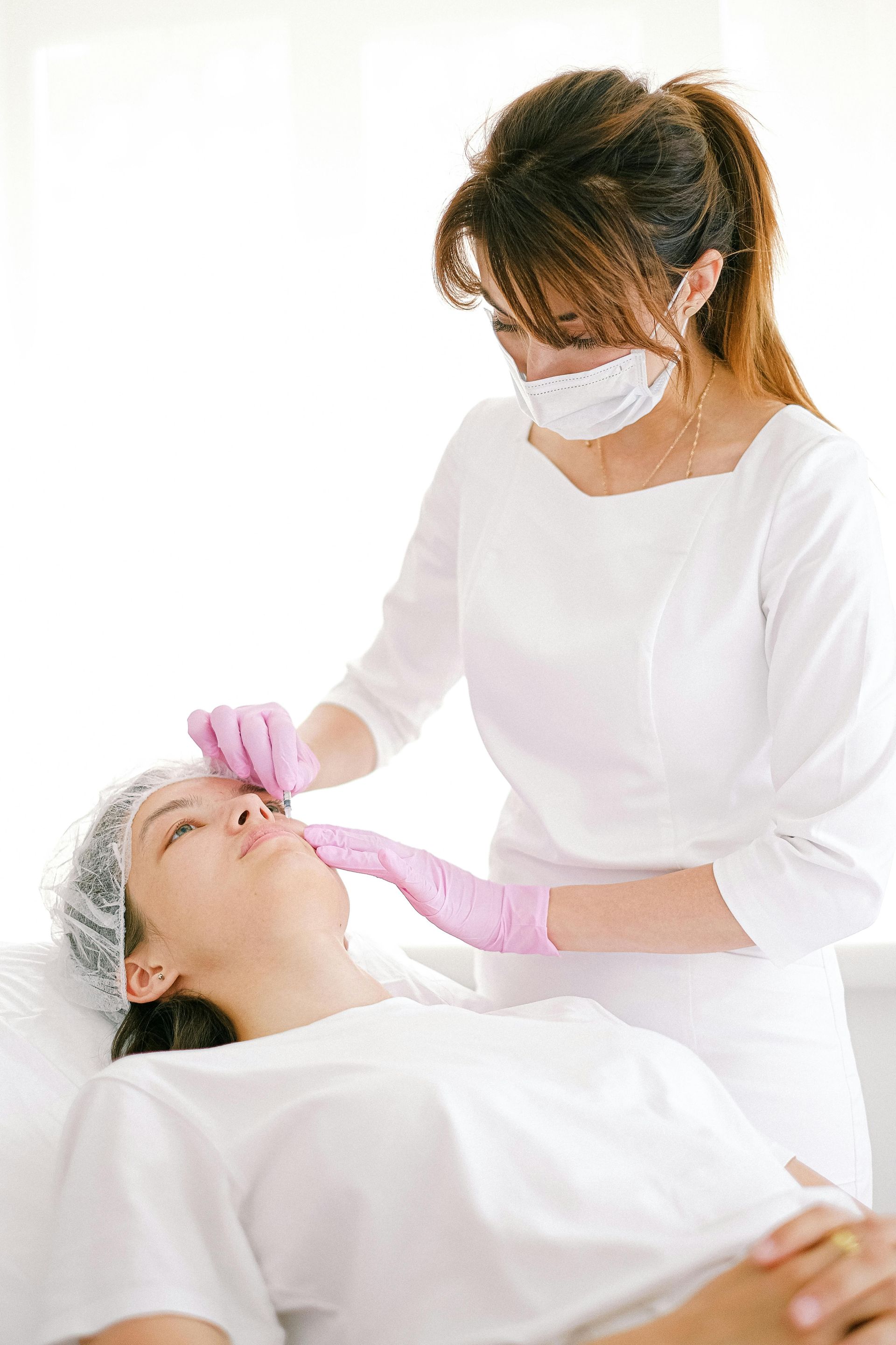 A woman receiving a cosmetic procedure from a healthcare professional in a clinic.
