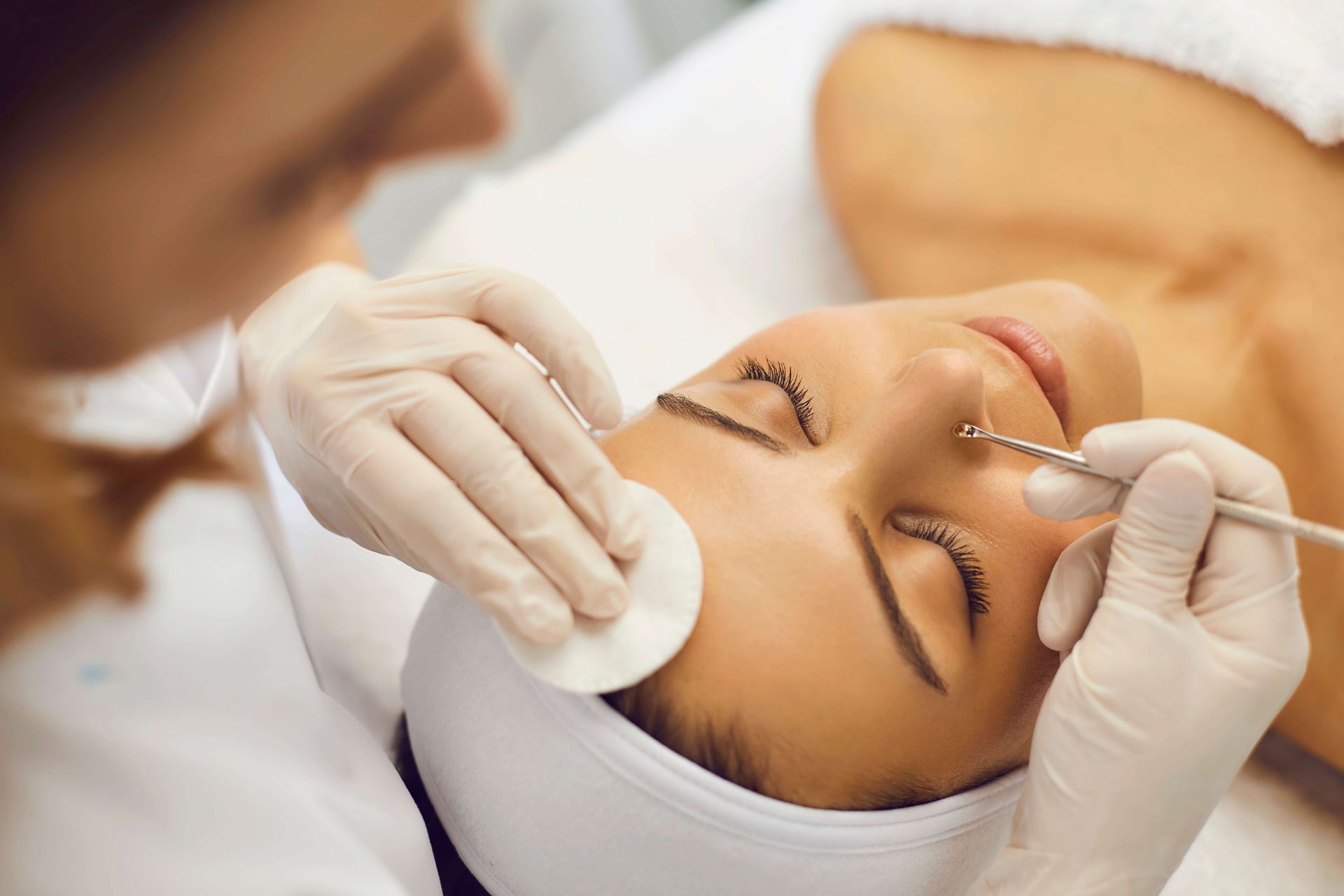 A person getting a facial treatment. Aesthetitician uses tools and cotton.