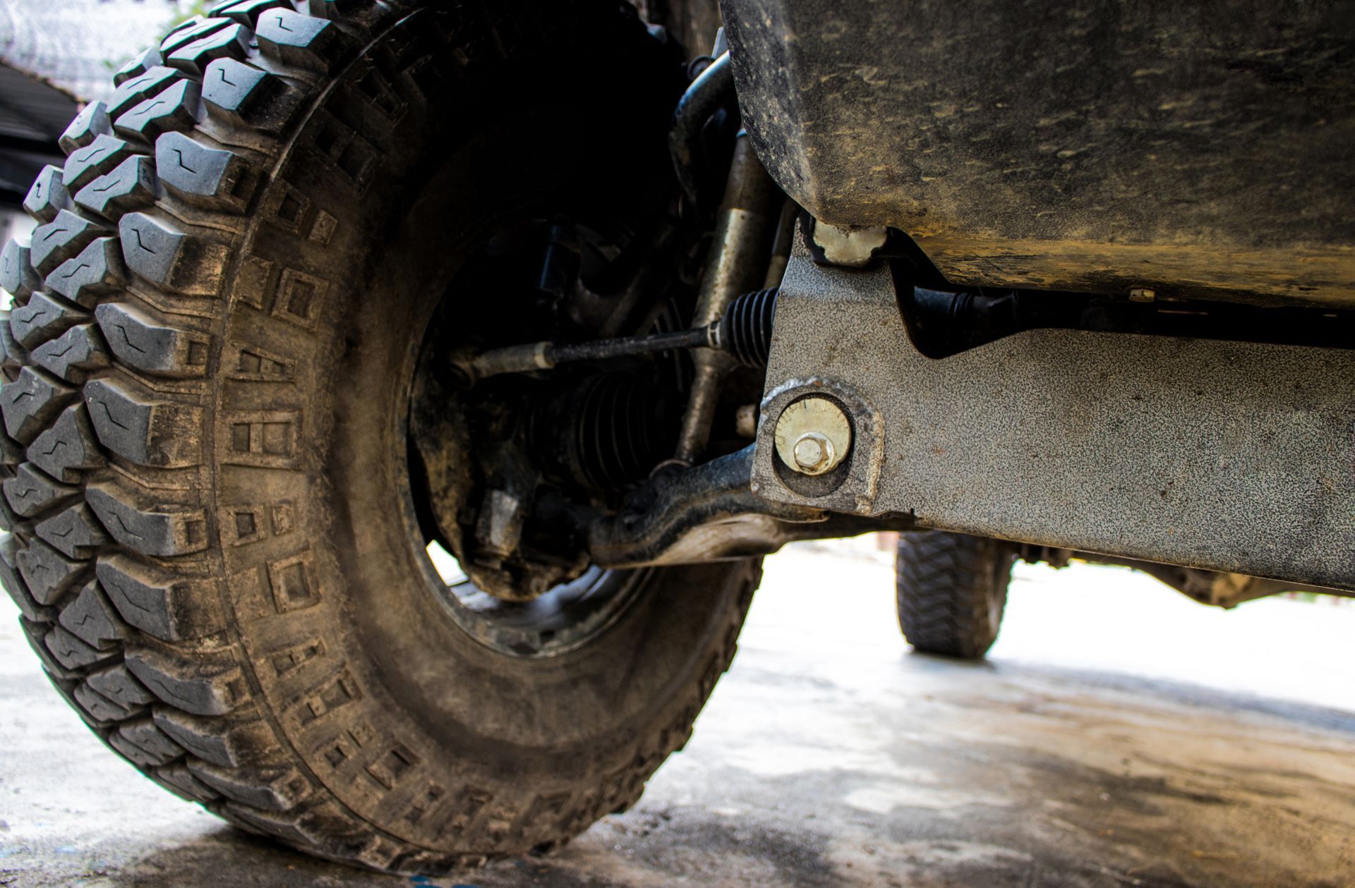 Close-up of an off-road tire and suspension under a muddy vehicle — PowerMaster Batteries Moree in Walgett, NSW