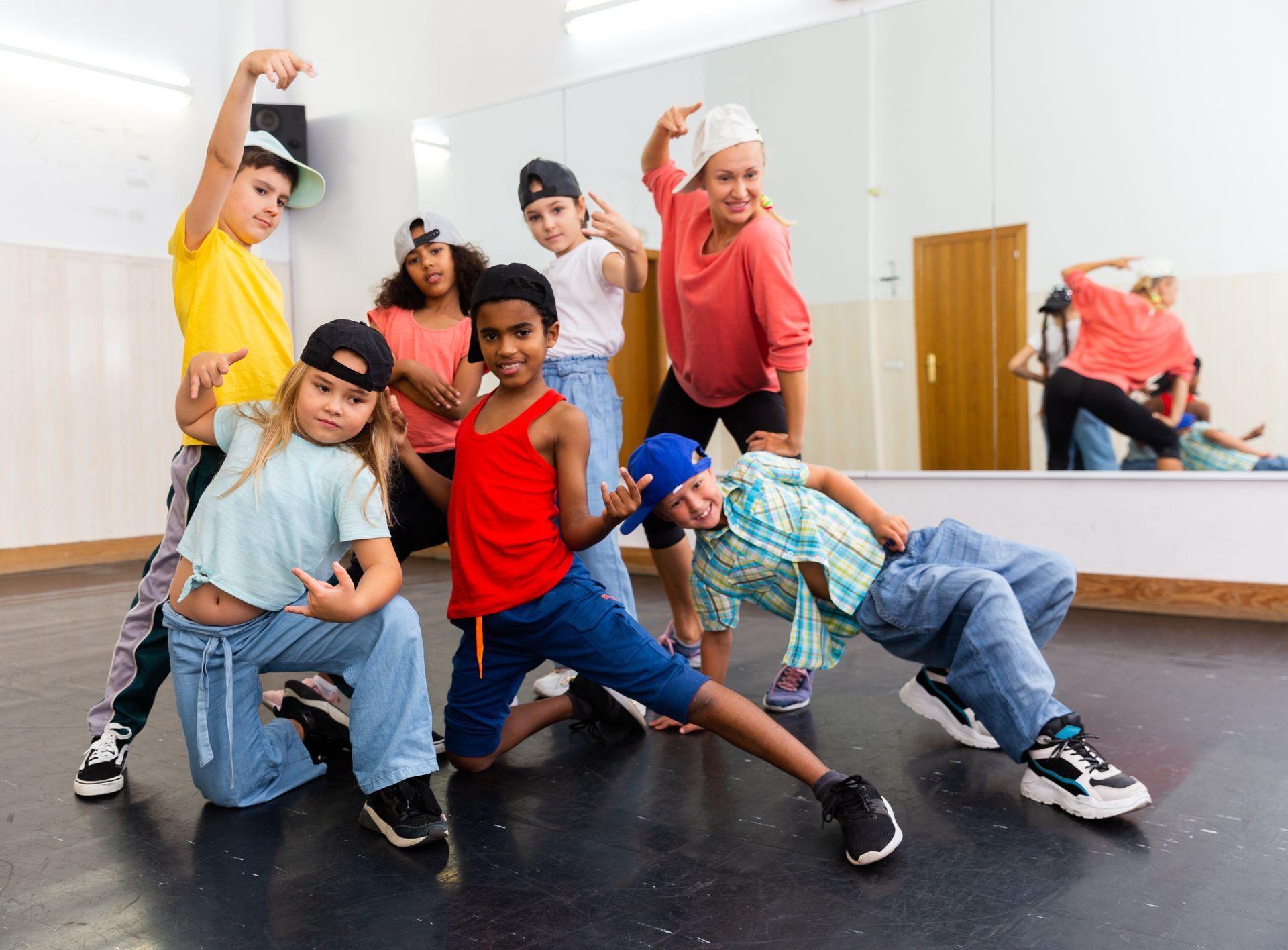 A group of kids in a dance studio posing confidently, wearing casual clothes.