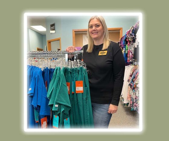 A woman is standing in front of a display of scrubs in a store.