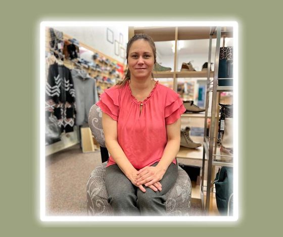 A woman is sitting in a chair in a shoe store.