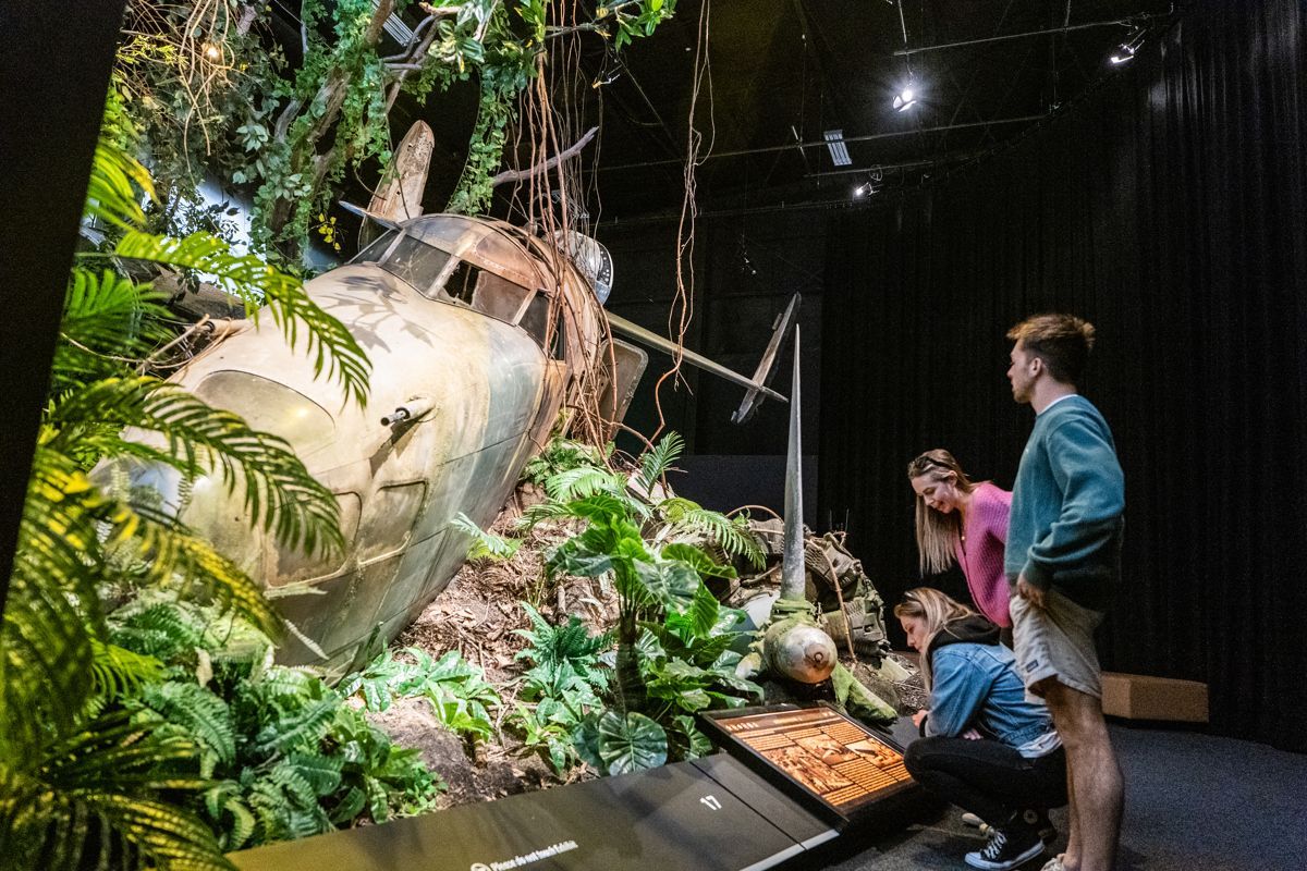 A group of people are looking at a crashed plane in a museum.