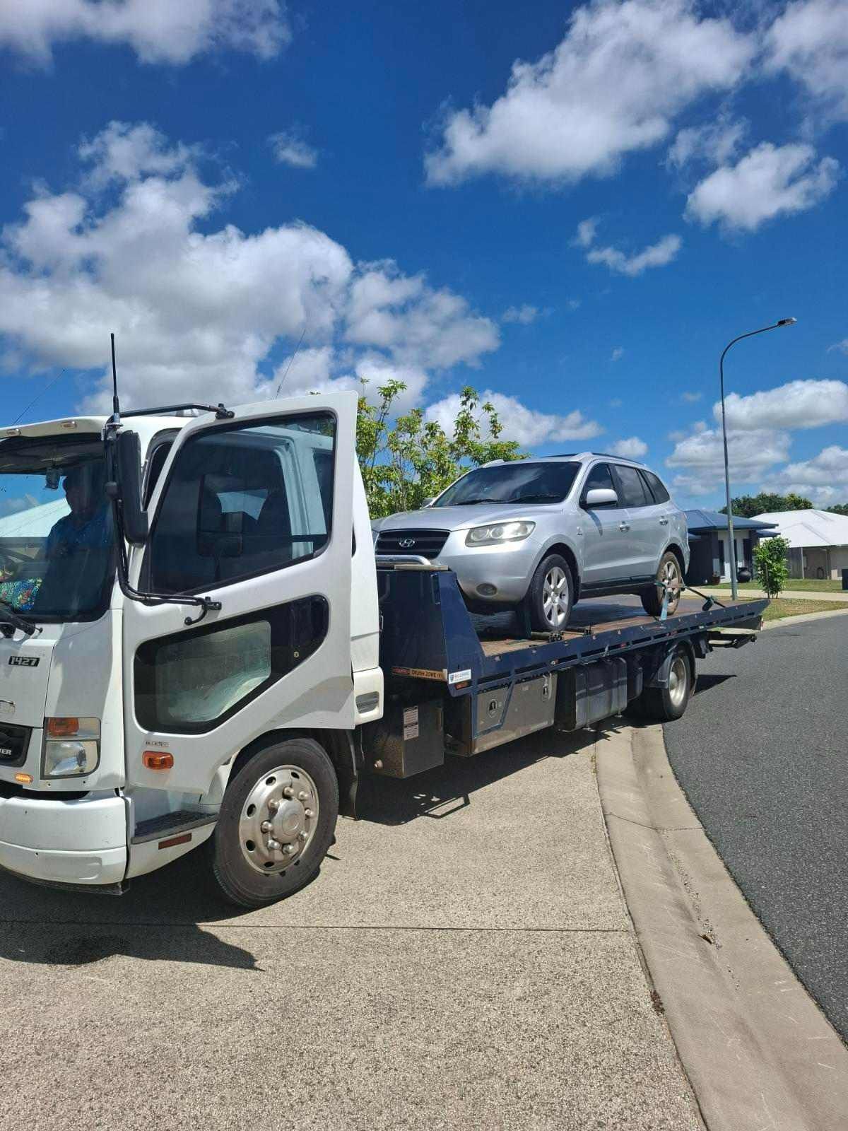 A Tow Truck With A Car On The Back Is Parked On The Side Of The Road — Rockhampton Towing And Transport in Gracemere, QLD