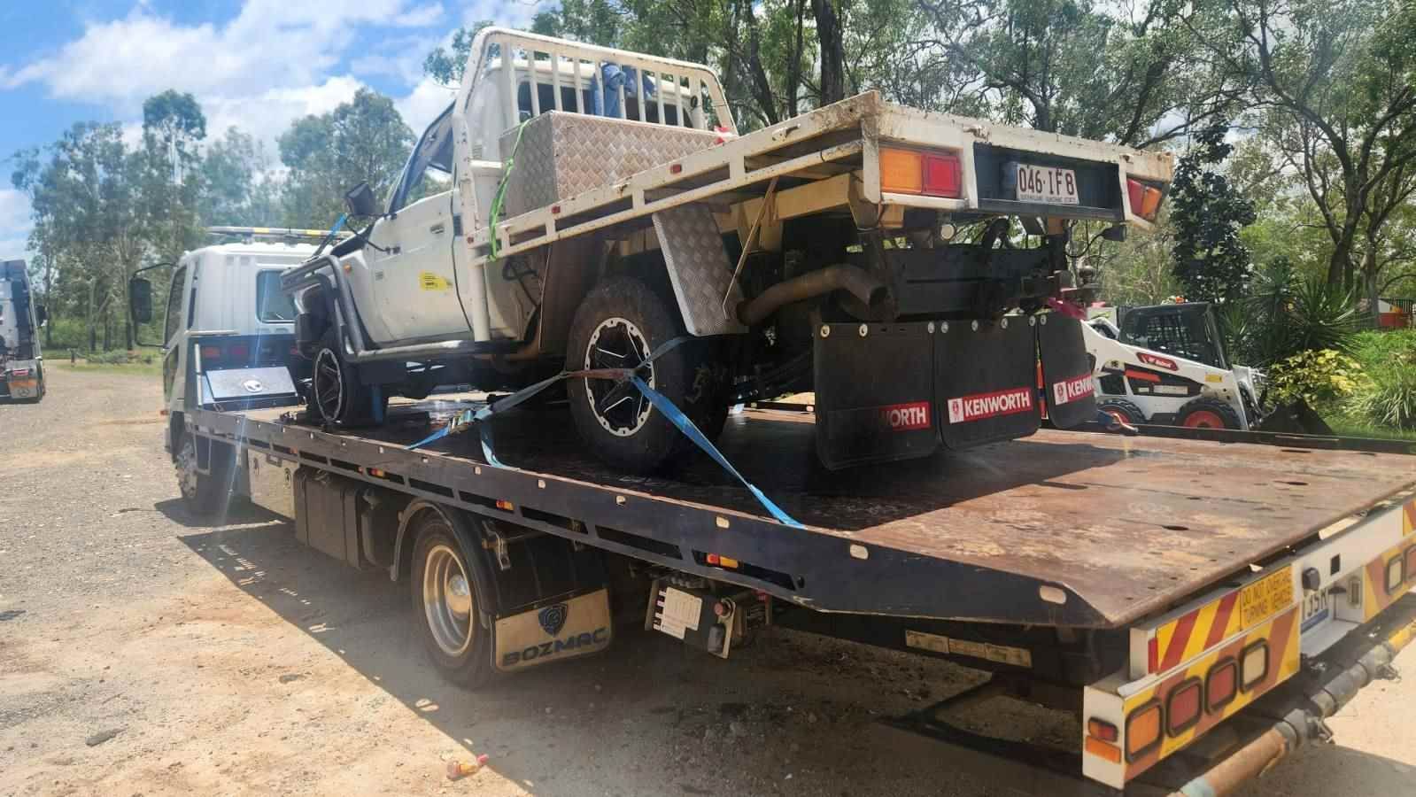A Tow Truck Is Carrying A Truck On The Back Of It — Rockhampton Towing And Transport in Gracemere, QLD