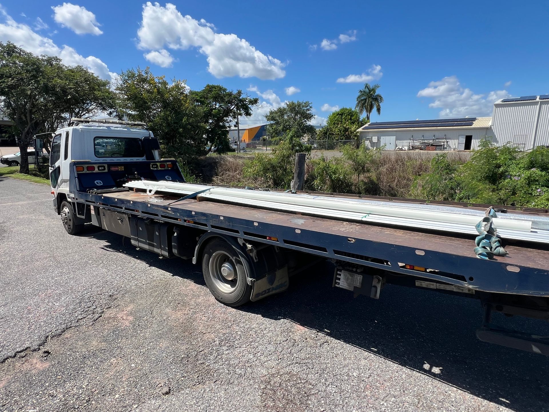 A Red Car Is Being Towed By A Tow Truck — Rockhampton Towing And Transport in Yeppoon, QLD