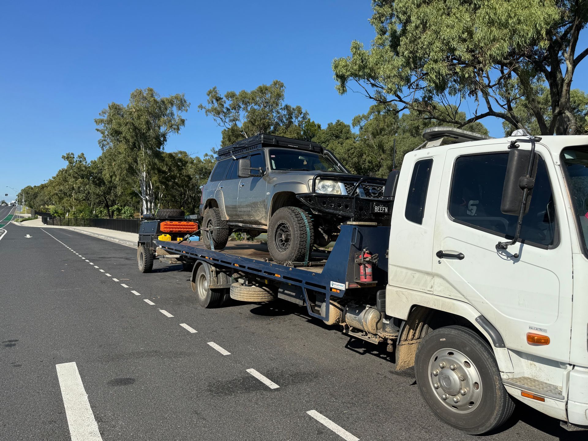 A White Car Is Being Towed By A Tow Truck — Rockhampton Towing And Transport in Gladstone, QLD