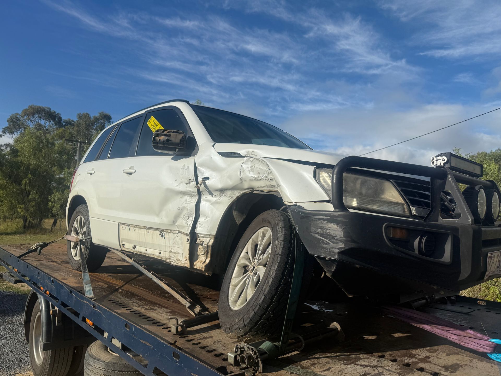 A Tow Truck Is Towing A Blue Car On A Highway — Rockhampton Towing And Transport in Yeppoon, QLD