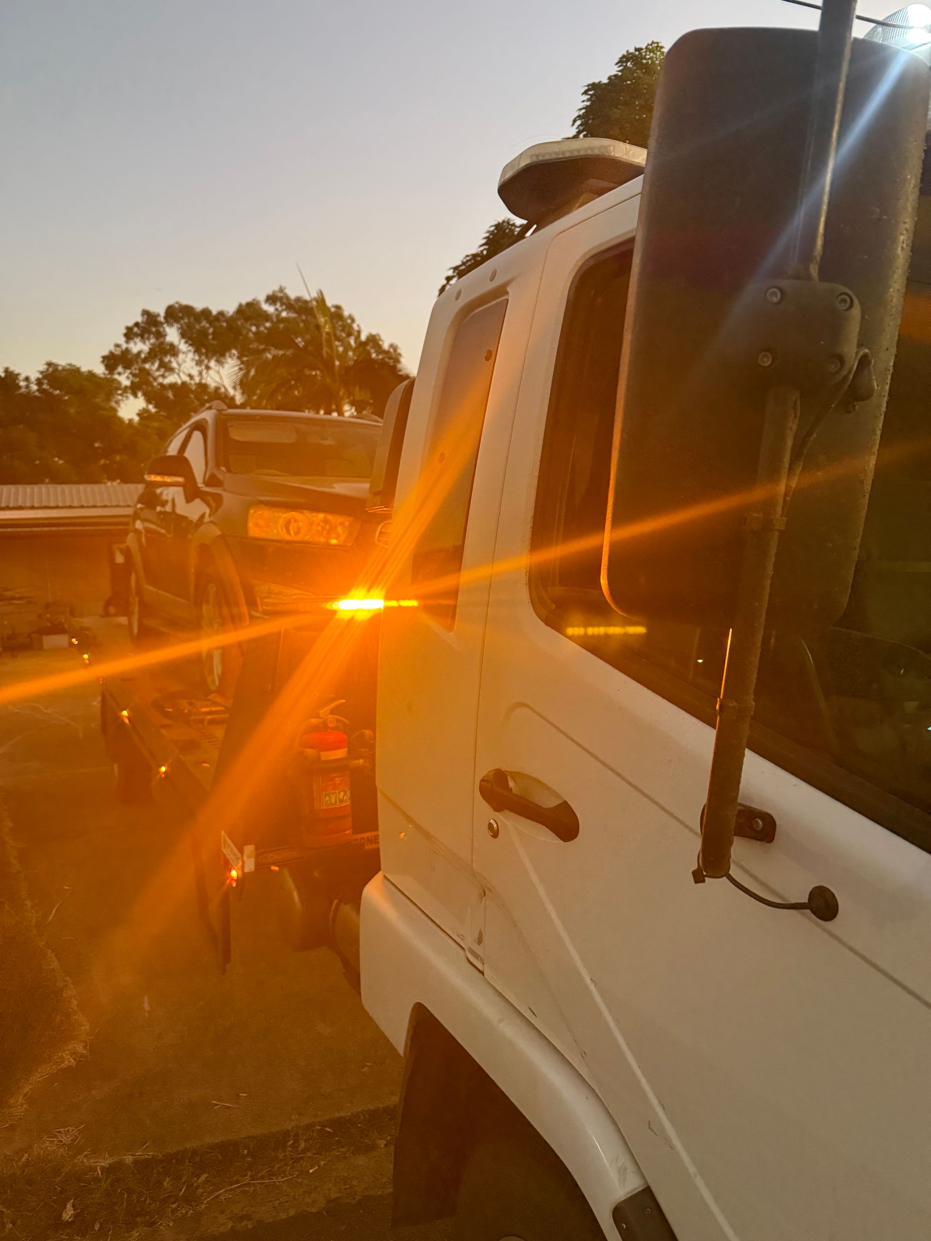 A Tow Truck Is Towing A Damaged Car On The Side Of The Road — Rockhampton Towing And Transport in Gracemere, QLD